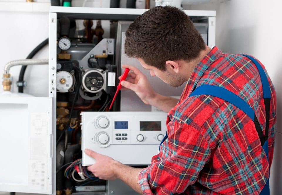 Technician checking a gas furnace with a multimeter.
