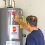 Man adjusting settings on a hot water heater in a residential setting.